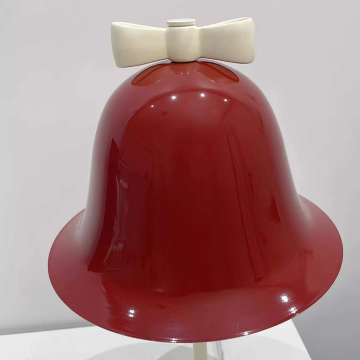 Red bell-shaped lamp with a cream bow accent, perfect for adding a playful touch to any decor.