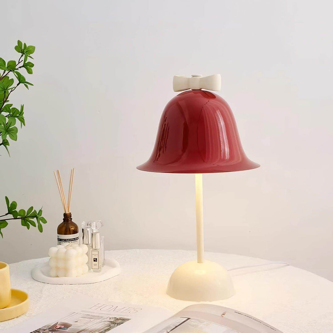 Charming red bell-shaped lamp with cream base and bow, perfect for cute bedside or dining room table decor.
