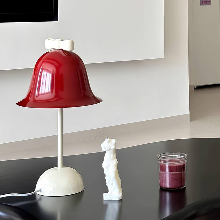 Red Nessino table lamp on a black table, styled with decorative figurine and candle for a chic home decor.