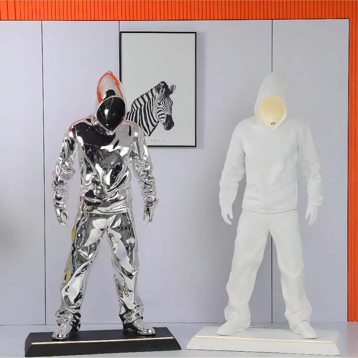 Art pieces featuring a shiny chrome figure in a hoodie and a white mannequin, adding modern flair to interior decor.