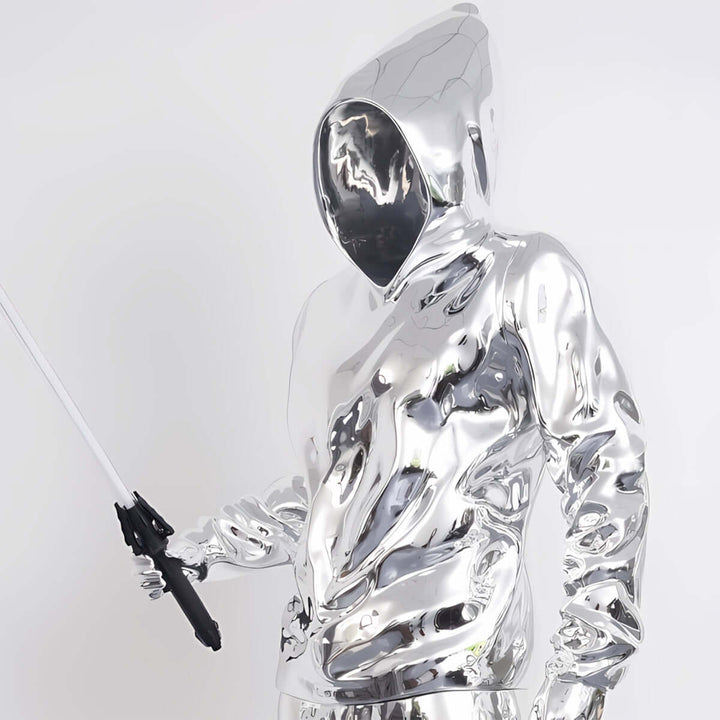 Sculptural silver figure in a hooded sweatshirt holding a lightsaber, reflecting a modern art aesthetic.