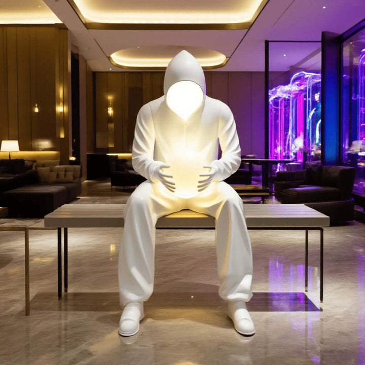 Sculptural floor lamp featuring a large white figure in a hooded sweatshirt, illuminating a modern living room space.
