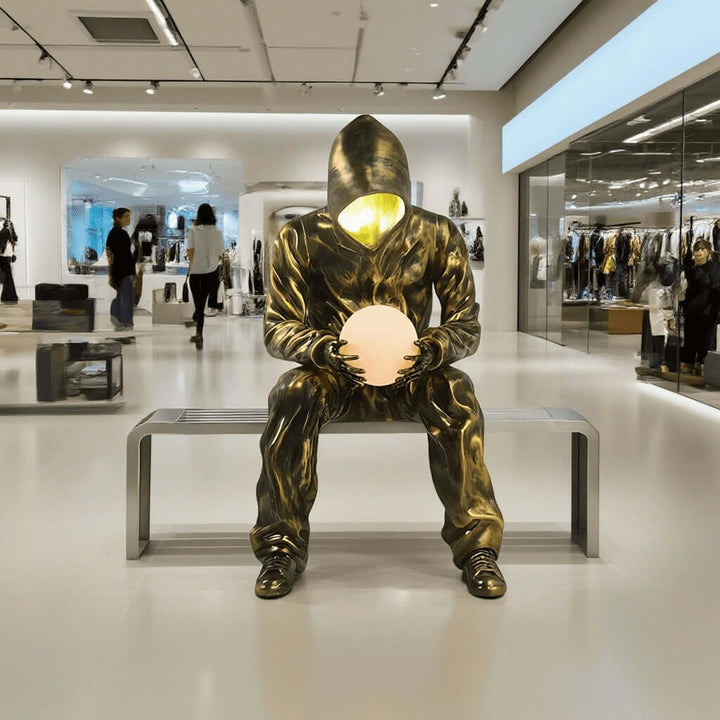 Sculptural floor lamp resembling a seated figure with a glowing orb, perfect for enhancing modern interior aesthetics.