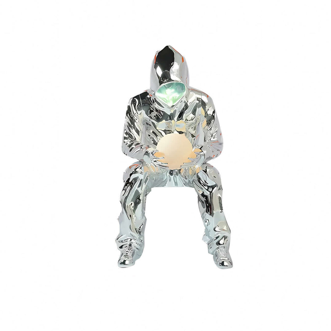 Sculptural floor lamp in chrome finish resembling a seated figure, ideal for art deco and modern living room decor.