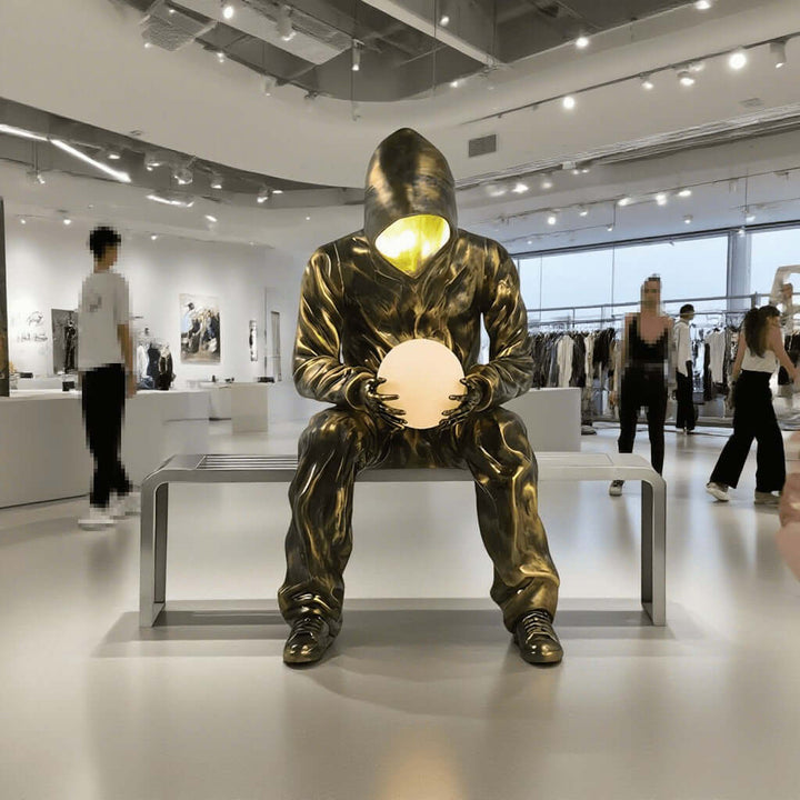 Sculptural floor lamp designed as a sitting figure holding a glowing orb, perfect for modern living room decor.