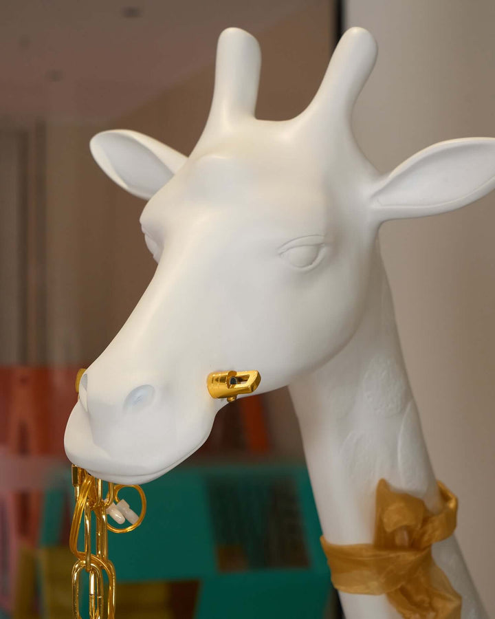 Sculptural giraffe floor lamp with a gold chain accent, ideal for art deco decor in living rooms.