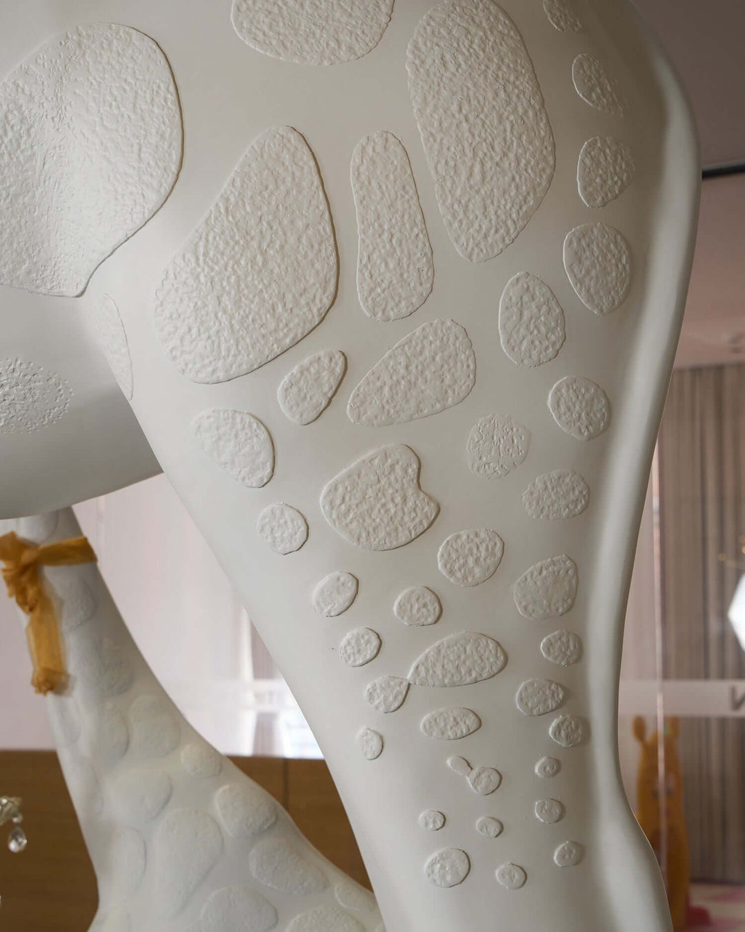 Close-up of the textured surface on the leg of a sculptural giraffe floor lamp, showcasing unique details.