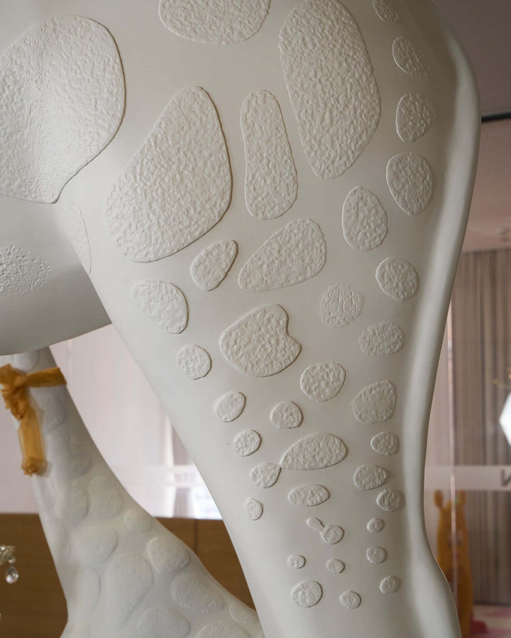 Close-up of the textured surface on the leg of a sculptural giraffe floor lamp, showcasing unique details.