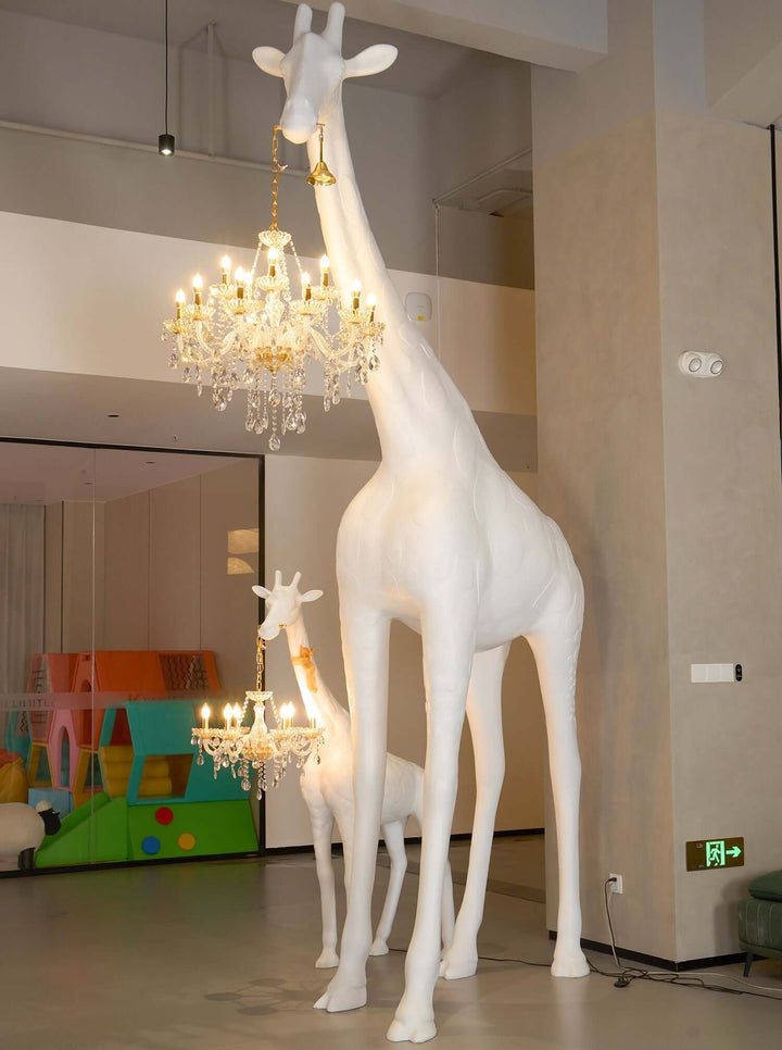 Sculptural giraffe floor lamp with chandelier accents in a modern interior setting.