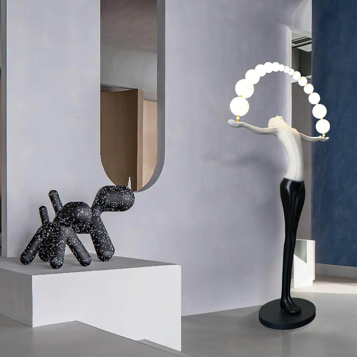 Sculptural floor lamp next to a decorative black dog statue in a modern interior setting.