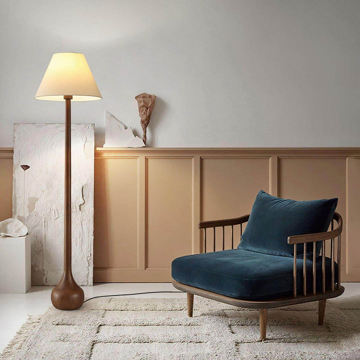 Osaka wooden floor lamp standing next to a cozy blue chair in a stylish living room, perfect for rustic decor.
