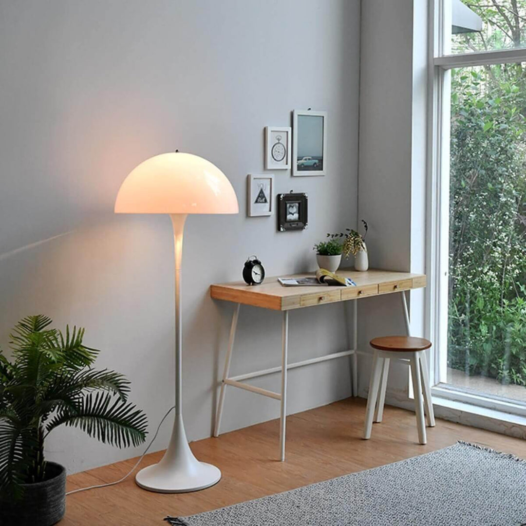 Stylish Panthella floor lamp in white illuminating a modern living room, complemented by a wooden desk and greenery.