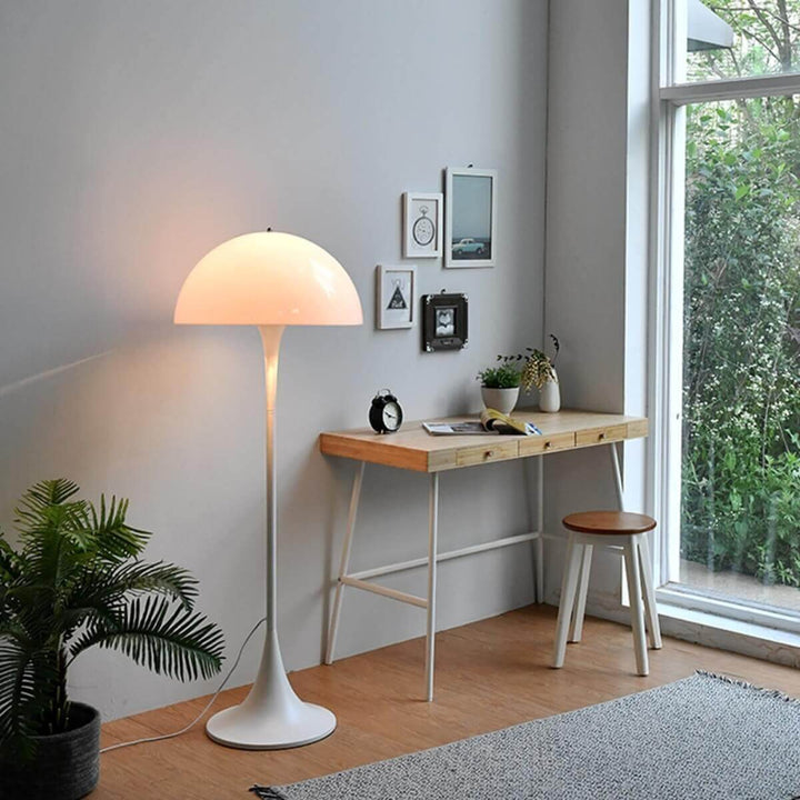 Stylish Panthella floor lamp in white illuminating a modern living room, complemented by a wooden desk and greenery.