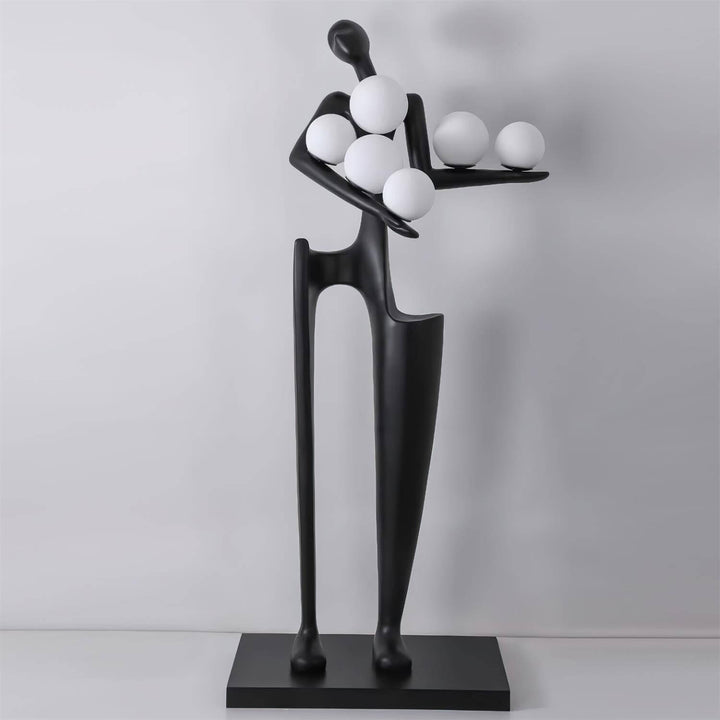 Sculptural floor lamp featuring an art deco design with a unique figure holding spherical lights in a modern living room.