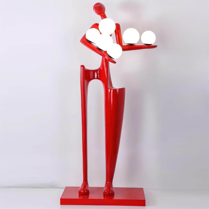 Sculptural floor lamp in red featuring a figure holding glowing orbs, ideal for modern art deco living room decor.