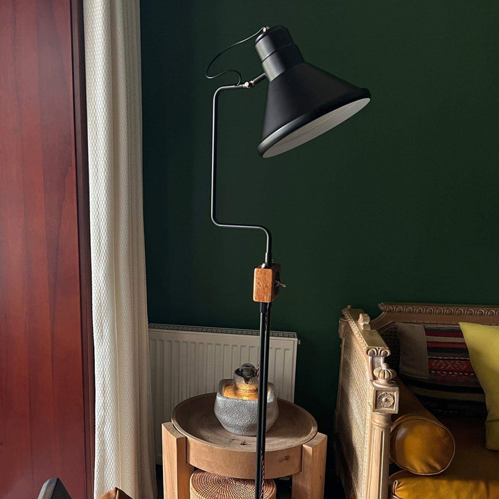 Retro Toia floor lamp in industrial style, black color, standing next to a cozy seating area, perfect for corners.
