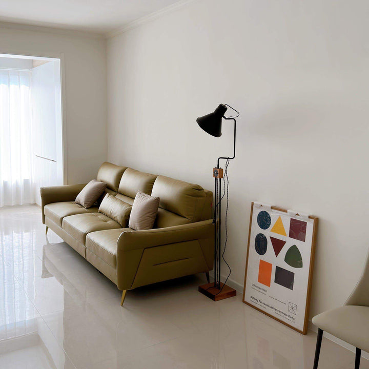 Stylish retro Toia floor lamp in a modern living room next to a green leather sofa and art print, enhancing ambiance.