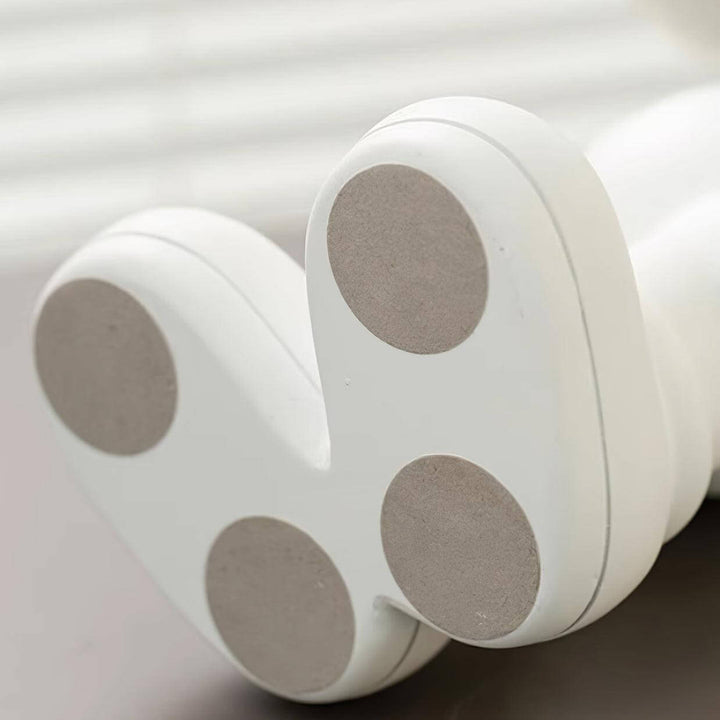 Close-up of the bottom of a modern white lamp showing soft, round pads for stability and protection on surfaces.