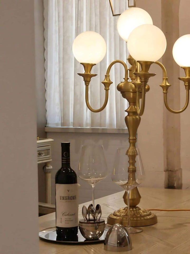 Solora brass table light with globes, paired with wine glasses and a bottle, perfect for mid-century modern living room decor.