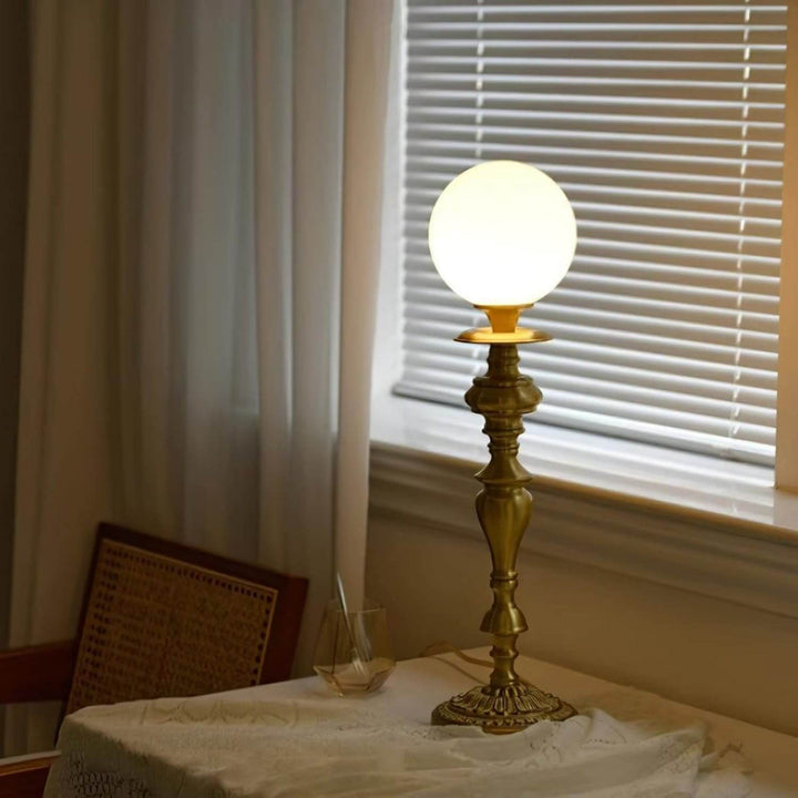 Brass lamp with vintage design and milk glass globe, perfect table light for living room decor.