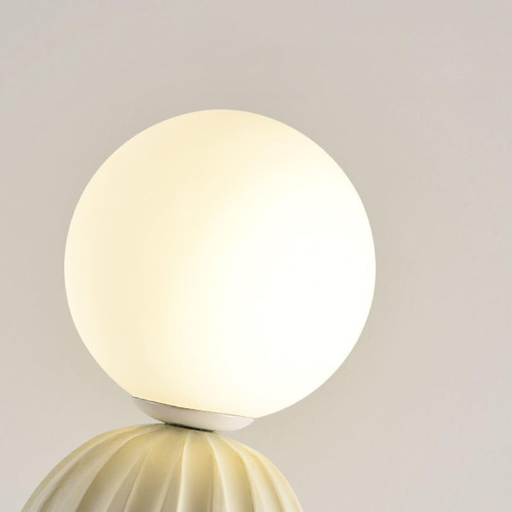 Sculptural white globe light atop an elegant base, perfect for modern decor and ambient lighting.