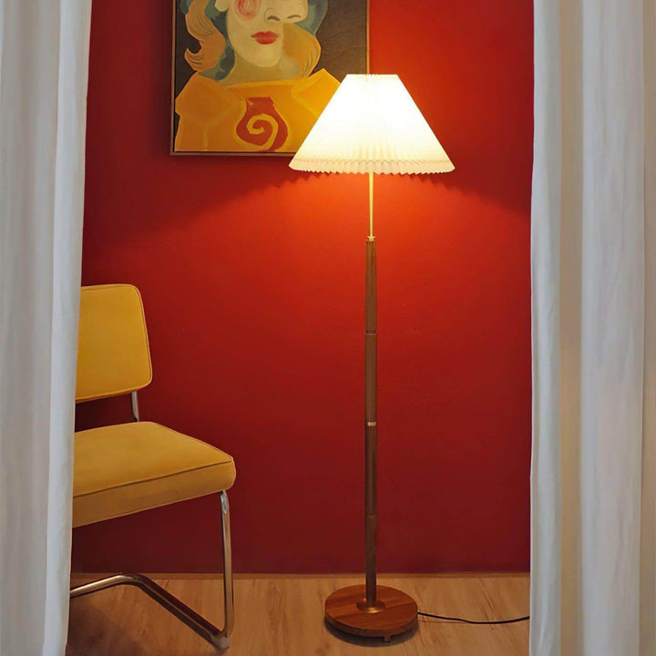 Suki Pleated Floor Lamp, a wooden mid century modern floor lamp, brightening a cozy corner beside a yellow chair.