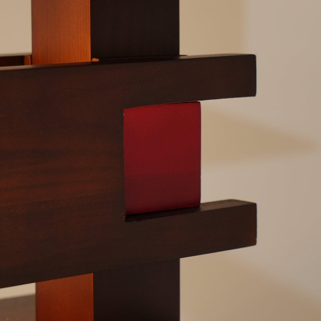Close-up of a wooden shelf structure with a red accent detail, showcasing modern design and craftsmanship.