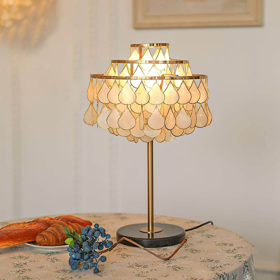 Teardrop shell table lamp with brass finish, perfect for coastal bedside decor, featuring a stylish design and warm illumination.