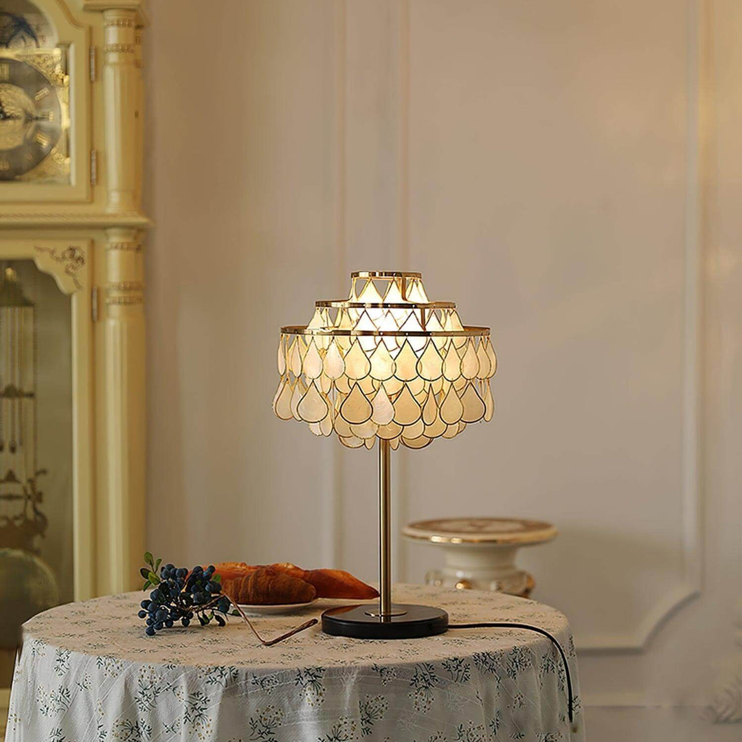 Teardrops shell table lamp with brass base, illuminating a cozy table setting in a luxury coastal decor.