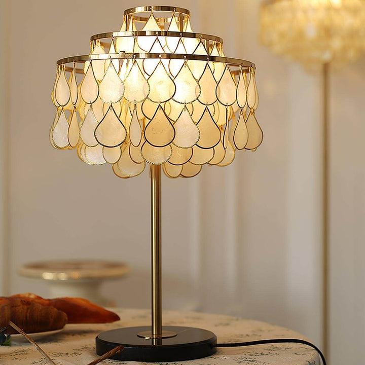 Teardrop shell table lamp in brass design, creating a coastal luxury ambiance for bedside or decorative use.