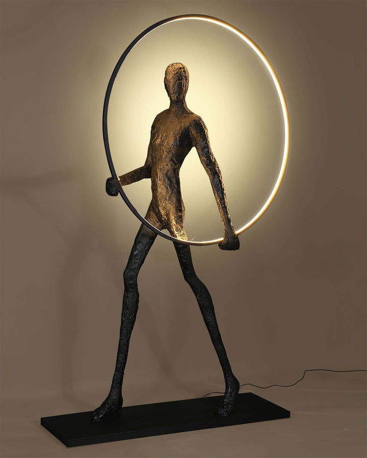Sculptural floor lamp resembling a human figure holding a circular light, perfect for art deco and modern living room decor.