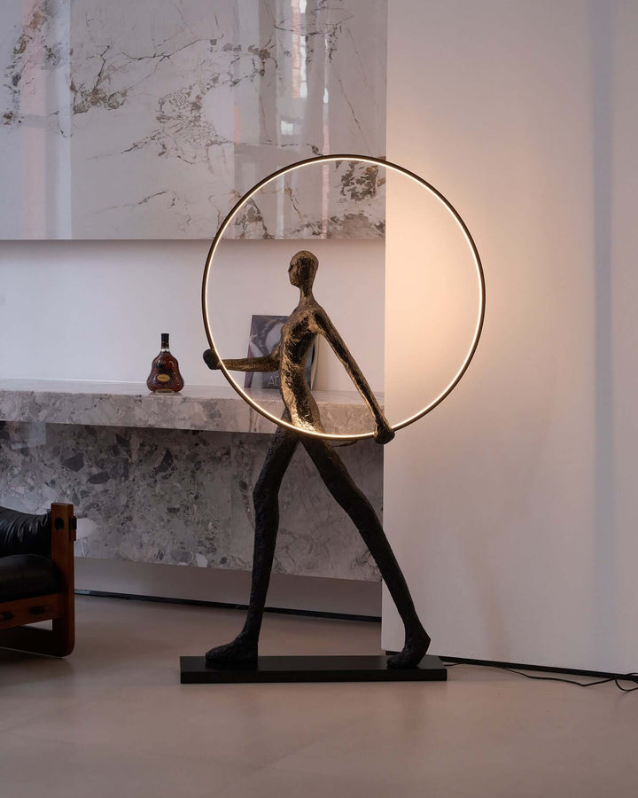 Sculptural Tivoro Ring Floor Lamp in art deco style, featuring a stylish figure holding a circular light in a modern living room.