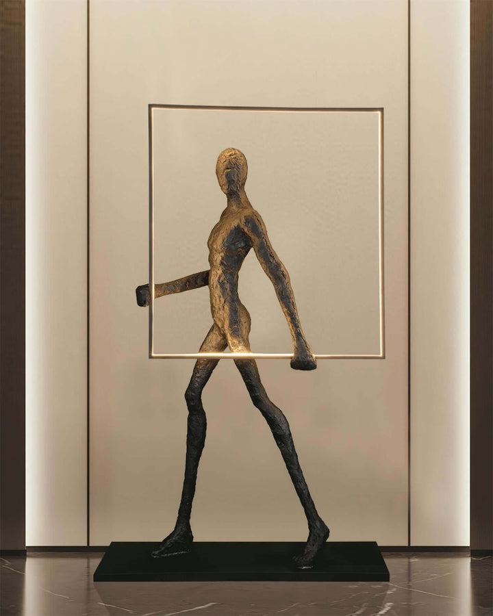 Sculptural bronze figure walking within a minimalist frame, elegantly styled for modern decor.