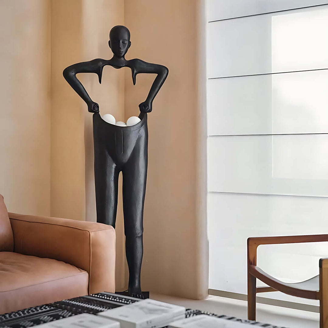 Sculptural black floor lamp resembling a figure holding eggs, designed for contemporary living room decor.