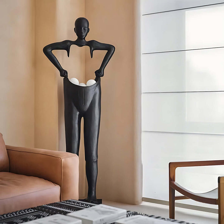 Sculptural black floor lamp resembling a figure holding eggs, designed for contemporary living room decor.