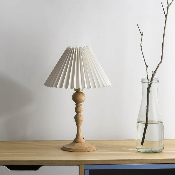 Zulu Pleated Table Lamp on a wooden table, featuring a vintage style with a wood base and pleated shade.