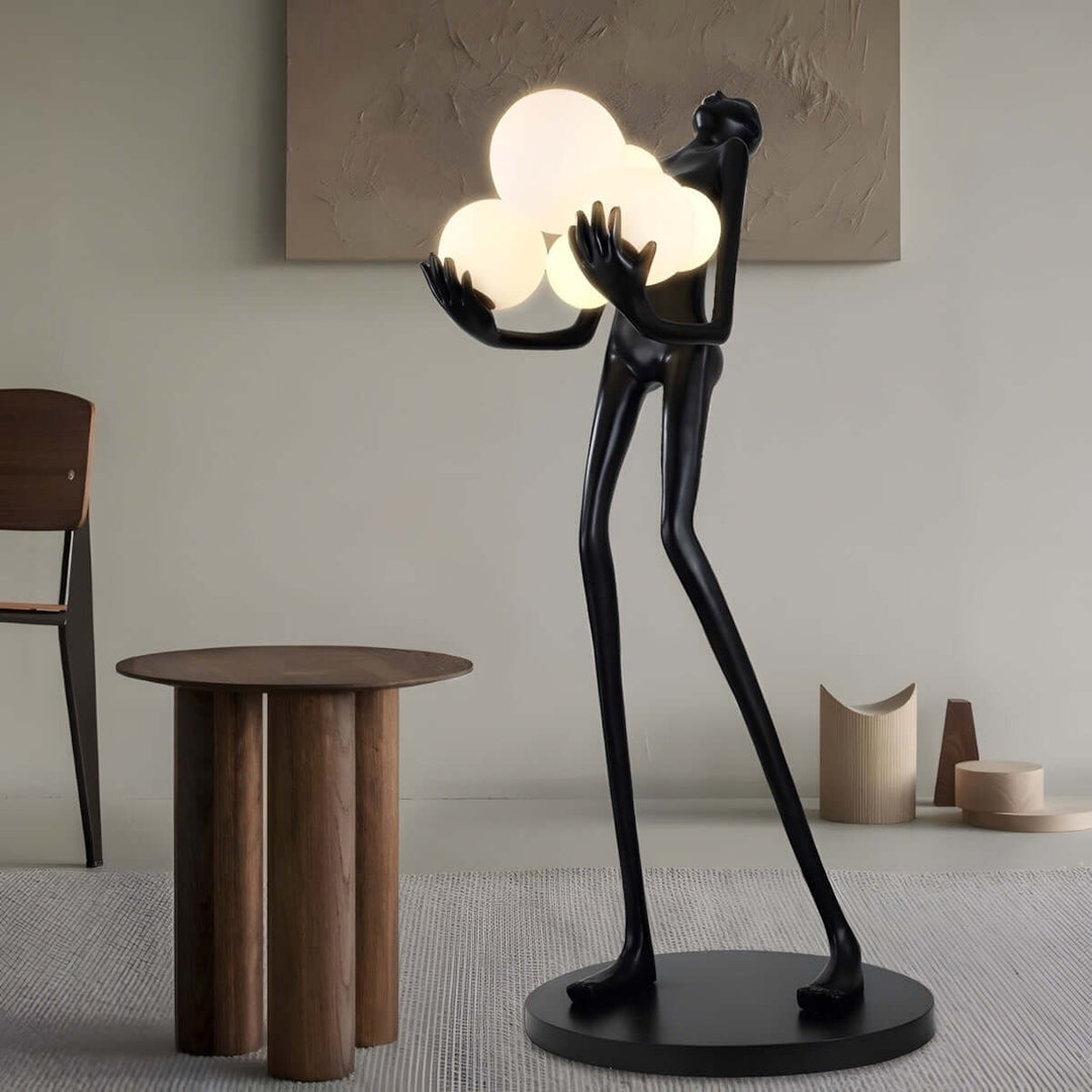 Sculptural art deco floor lamp in living room, featuring a tall figure holding glowing orbs, enhancing contemporary decor.