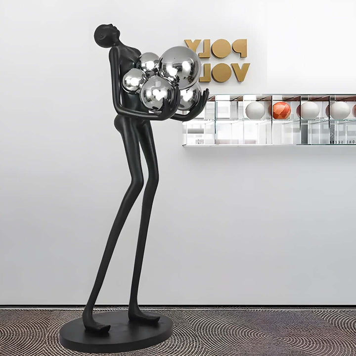 Sculptural floor lamp featuring a slender figure holding reflective spheres, perfect for modern art deco interiors.