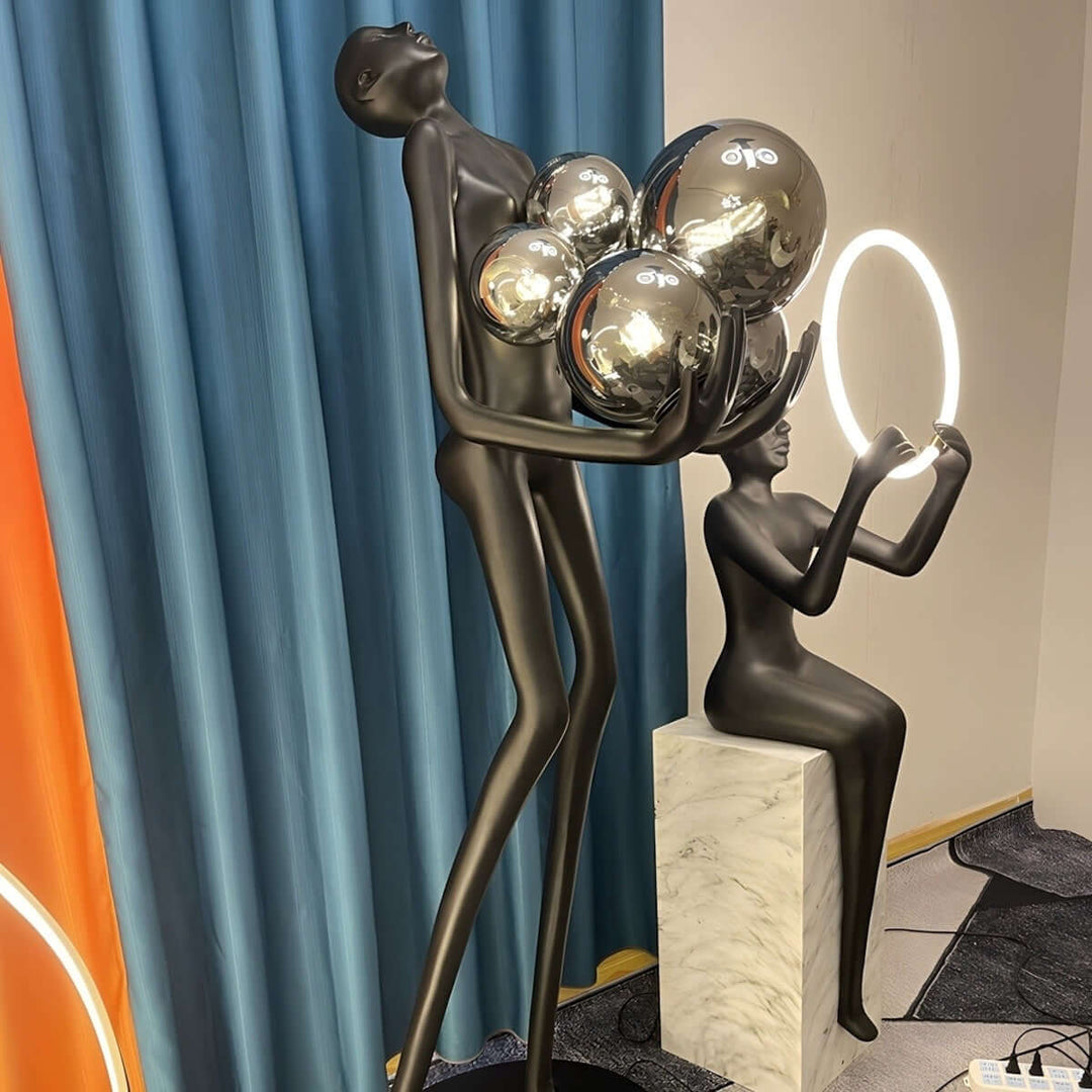 Sculptural floor lamp featuring a black figure holding reflective spheres, stylish decor for modern living spaces.