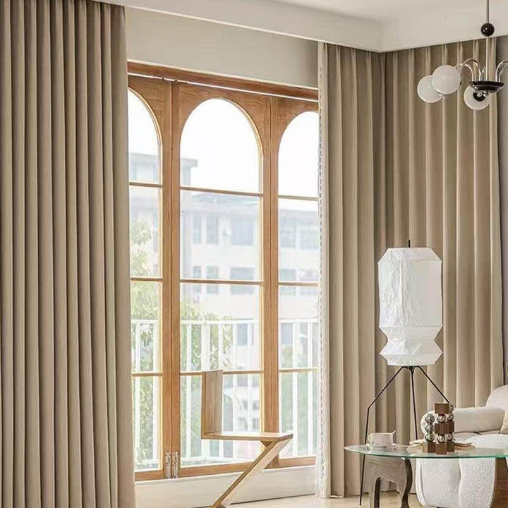 Decorative white Japanese paper floor lamp beside window in a stylish living room with neutral curtains.