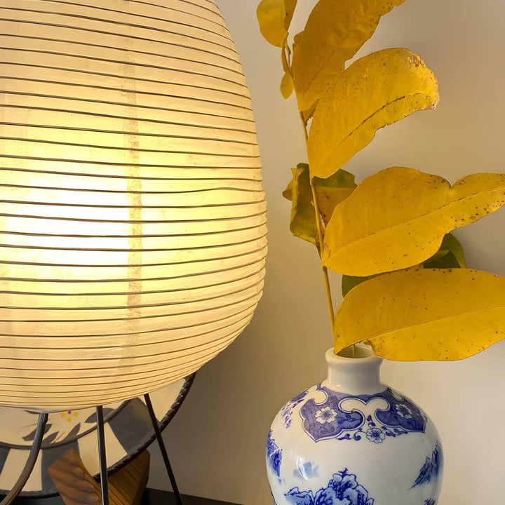Washi paper Bonn table light beside a decorative vase with yellow leaves, adding a modern touch to any bedroom decor.
