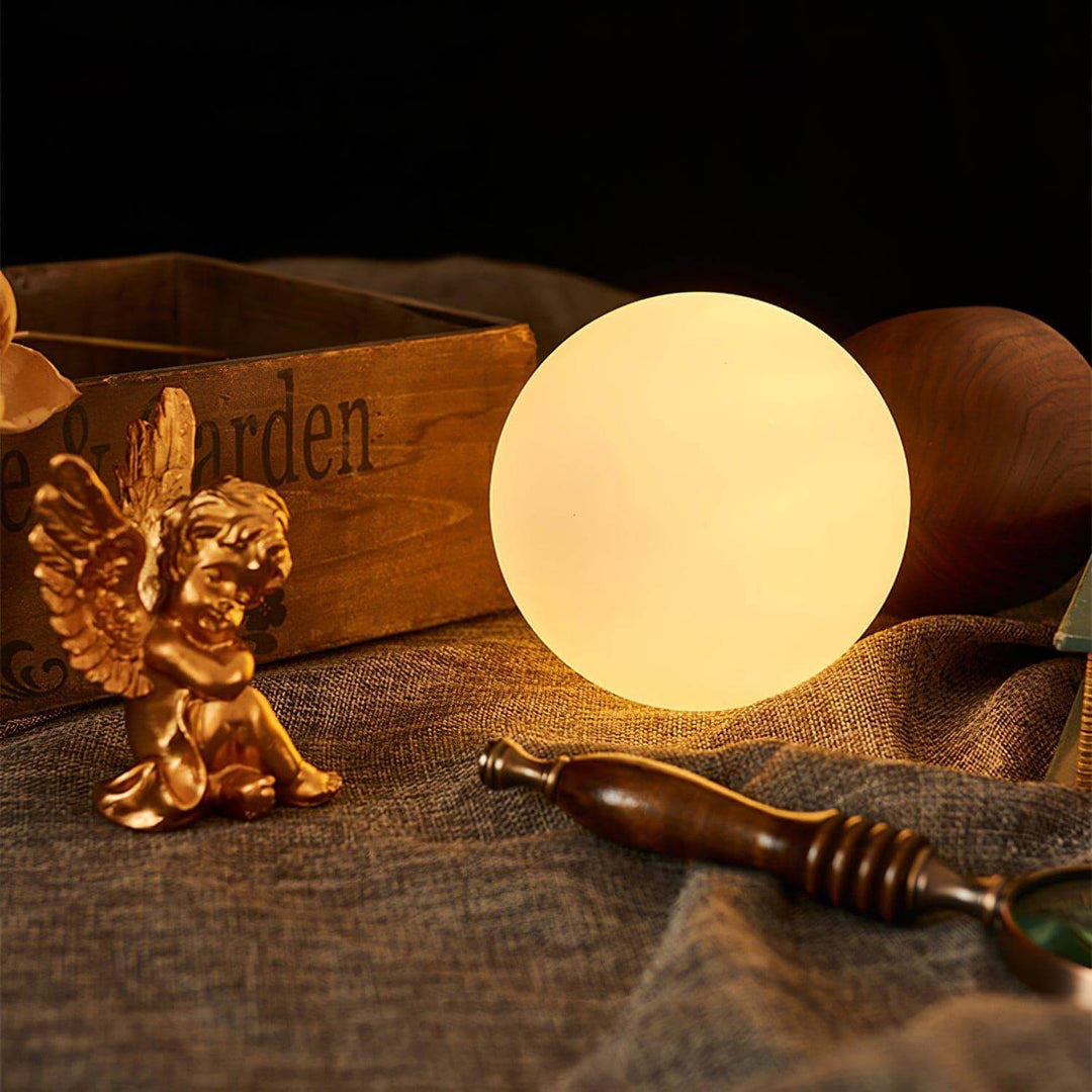 Wood knuckle table lamp with vintage milk glass design, glowing softly beside decorative figurines and wooden accents.