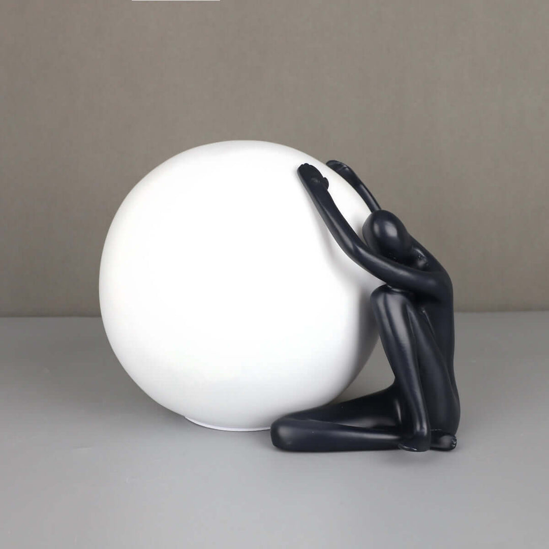 Zelvora sculptural table lamp featuring a human figure holding a white sphere, stylish art deco design for living room lighting.