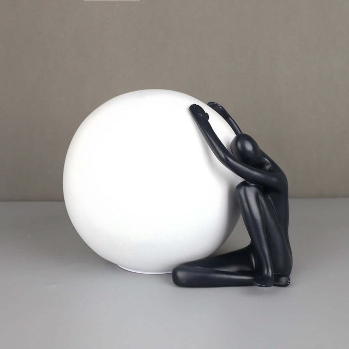 Zelvora sculptural table lamp featuring a human figure holding a white sphere, stylish art deco design for living room lighting.
