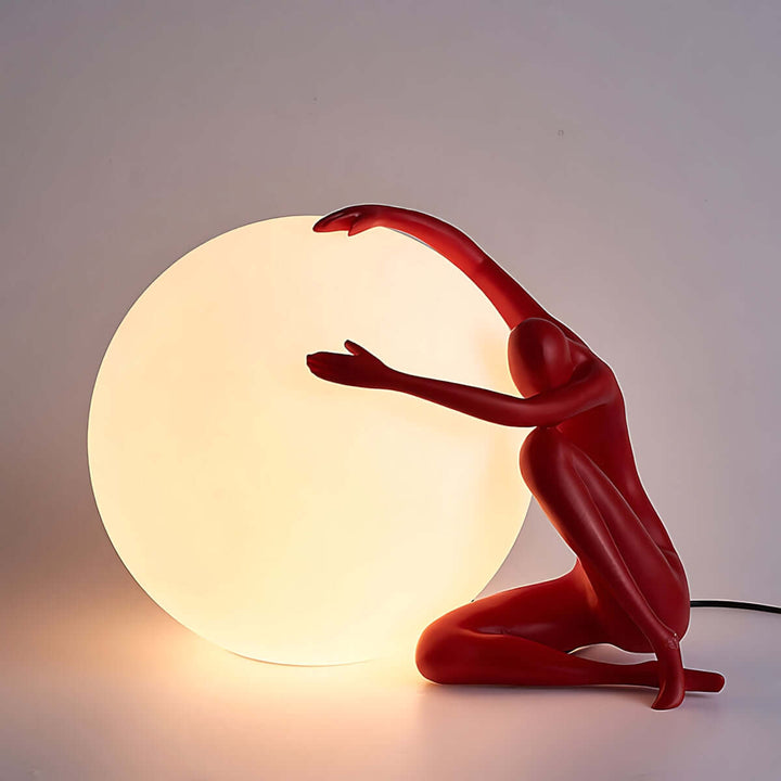 Zelvora sculptural table lamp with red figure holding a glowing orb, perfect for artistic decor in living rooms.