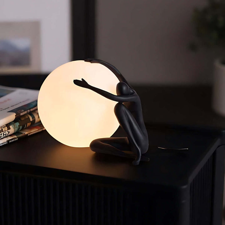 Zelvora sculptural table lamp, art deco style, featuring a black figure holding a glowing orb, perfect for living room decor.