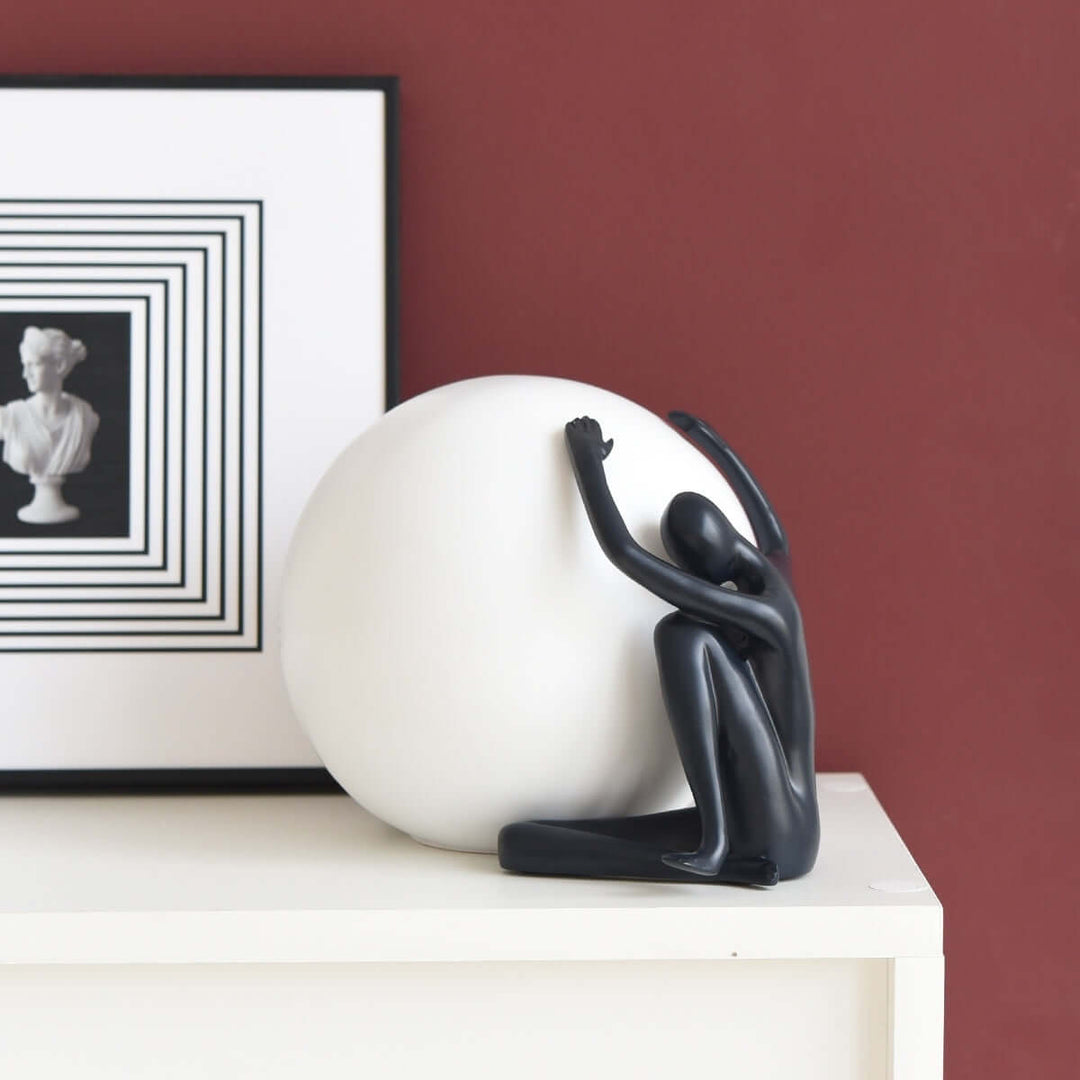 Zelvora sculptural table lamp showcasing a black figure embracing a white sphere on a stylish tabletop.