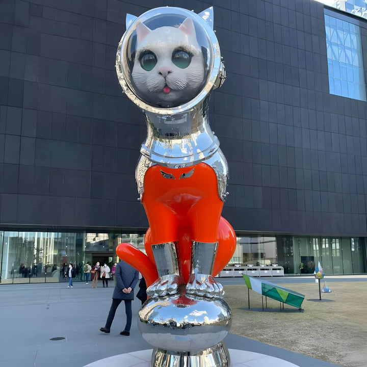 Colorful cat sculpture with an astronaut helmet, showcasing playful art in a modern outdoor setting.