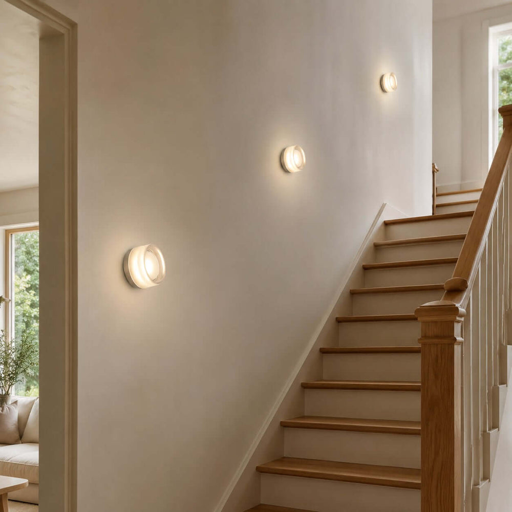Round Dimple wall sconces lighting a stairway wall.