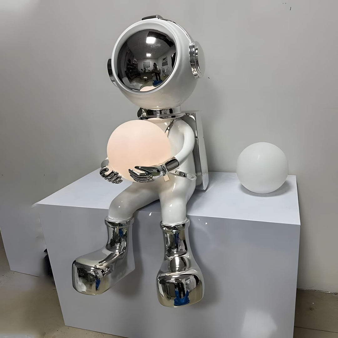 Sculptural astronaut lamp holding a glowing orb, perfect for modern decor and unique lighting.